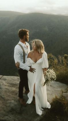 a man and woman standing on top of a mountain