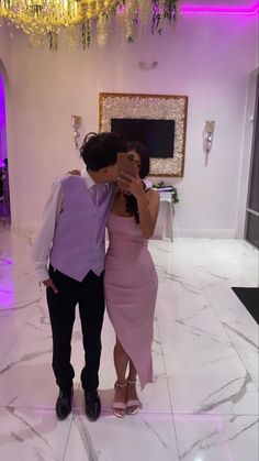 a man and woman taking a selfie in a room decorated with chandeliers