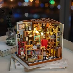 a doll house made out of books on top of a table with lights in the background