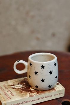 a coffee cup sitting on top of a wooden table next to a book with black stars