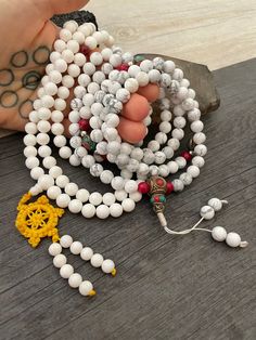 Beautiful Howlite Mala from Nepal and Mountain shell beads Mala necklace. You can choose between the mala that is made with howlite beads (white with gray) and mix metal beads from Nepal, or the all white mala necklace, which is made with mountain shell beads and a yellow mantra symbol. A unique praying mala that can be used as a necklace or as an ornament. The mala has no clasp, you wear it over the head. --The Mala with the metal beads and the red beads has a total length of 48.2cm- 19 inch lo Adjustable White Mala With Gemstone Beads, Adjustable White Mala With 8mm Beads, White 108 Beads Mala For Meditation, Hand-strung White Mala With Round Beads, Bohemian White Hand-strung Mala, Buddhist Mala, Wiccan Necklace, Yoga Lover Gift, 108 Mala Beads