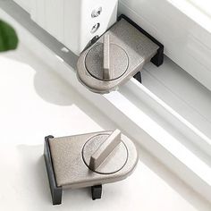 two metal latches on the side of a window sill, one is open and the other is closed