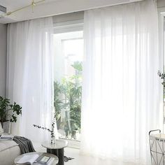 a living room filled with furniture and white curtains