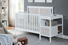 a baby crib in a nursery room with gray walls and white furniture, including a teddy bear