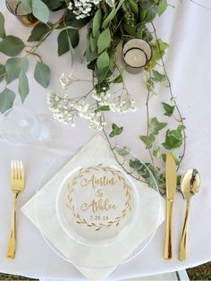 the table is set with goldware and greenery