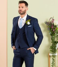 a man in a blue suit standing next to flowers