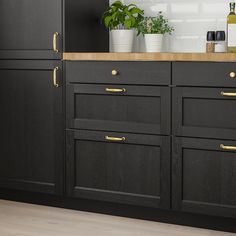 a kitchen with black cabinets and gold handles