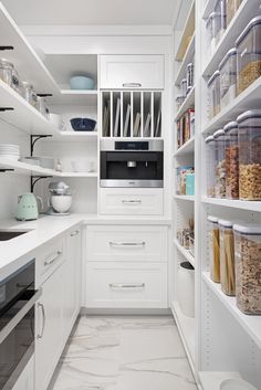 an organized pantry with white cabinets and drawers