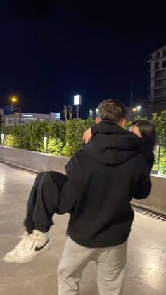 two people are hugging while standing on a skateboard ramp at night, one person has his arm around the other's back