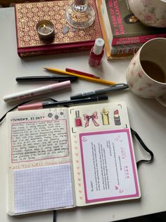 an open notebook sitting on top of a table next to a cup of coffee and other items