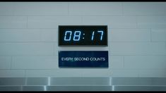 a clock that is on the side of a wall next to a sign saying every second counts