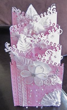 a pink and white greeting card with sequins on the edges, decorated with bows