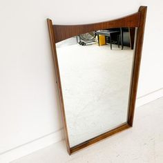 a mirror sitting on top of a white floor next to a wall