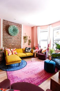 a living room filled with lots of furniture and colorful rug on top of a hard wood floor