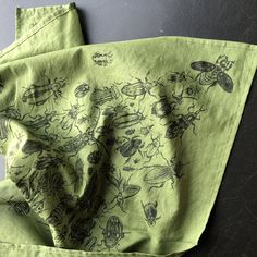 two green napkins with bugs and bees on them