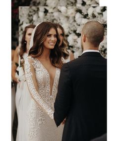 a bride and groom standing in front of a flower covered wall at their wedding ceremony