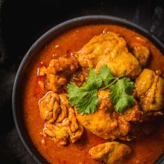 a bowl filled with chicken curry and garnished with cilantro