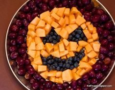 a plate with grapes, apples and cheese in the shape of a jack - o'- lantern