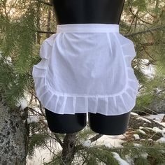 the back of a woman's white skirt hanging from a tree in the snow