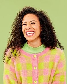 a smiling woman with curly hair wearing a colorful sweater