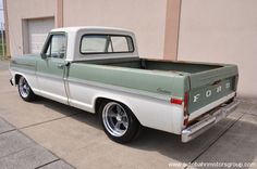 an old green and white truck parked in front of a building