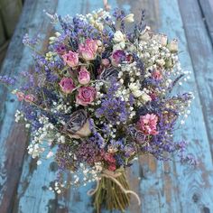 a bouquet of flowers sitting on top of a wooden table next to a blue wall