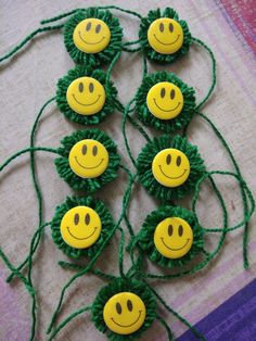 green string with yellow smiley face buttons on it and some thread in the middle to make them look like they are smiling