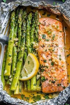 salmon and asparagus in foil with lemon wedges on the side for garnish