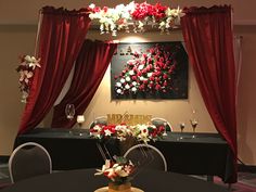 a black table with red curtains and flowers on it