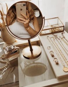 a woman taking a selfie in front of a mirror with jewelry on the table