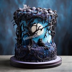 a cake decorated with blue frosting and spooky trees on top of a table