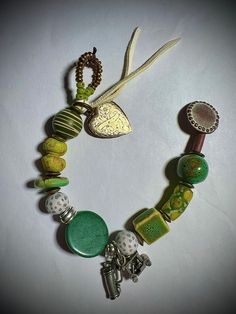 Love to play golf?  This is for you! (Or maybe a gift for the golf lover you love).  Beautiful beads in shades of green grass and sunshine (including a lovely green turquoise disc) are mixed with a few golf balls and adorned with two pewter charms...a golf cart and a golf bag!   I finished it off with a vintage gold heart charm and a strip of white leather. Lightweight and easy to wear out on the course. 8" long fits a medium (6-61/2") wrist.  (I can adjust the length if needed...just message your wrist measurement.) Very unique! Thank You for shopping handmade! Handmade Green Heart-shaped Bracelet, Green Heart Beads Bracelet Jewelry, Green Heart Beads Bracelet, Adjustable Green Heart-shaped Beaded Bracelets, Green Beaded Charms Bracelets As Gift, Green Bracelets With Charms And Round Beads, Green Beaded Bracelets With Charms As Gift, Green Bohemian Bracelets With Charms, Bohemian Green Bracelets With Charms