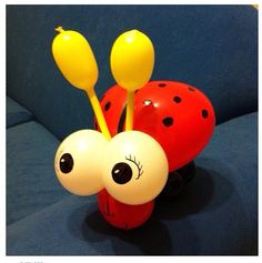 a ladybug vase with two yellow balloons sticking out of it