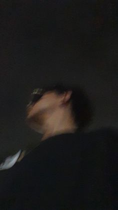 a blurry image of a man holding a cell phone to his ear and looking up at the sky