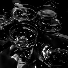 there are many wine glasses sitting on top of each other in this black and white photo