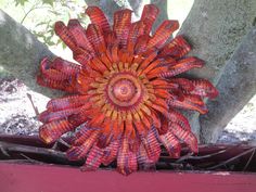 an orange and yellow flower sitting on top of a red bench next to a tree