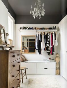 a closet with clothes hanging from the ceiling and a chandelier in the corner