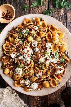 a white plate topped with pasta covered in fettuccine and cheese next to a wooden spoon