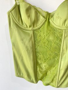 Vintage Victoria’s Secret Lime Green Bustier. A cutesy femme bustier with lace panel going down the front of the bodice and along the tops of the cups. Has boning and underwire. Delicate flower pattern stitched into the silk. Pink bow with circular rhinestone buckle adorning the left strap. In excellent condition. Body is a poly blend, bow is 100% silk. Hand wash cold. Marked size 36B. Approximate Measurements: Cup width: 6" Cup height without lace: 4" Underarm to underarm: 16" Length: 18" Lace Corset With Sweetheart Neckline And Built-in Bra, Lace Corset With Sweetheart Neckline And Lace Bodice, Coquette Lace Corset With Underwire, Lace Coquette Underwire Corset, Coquette Lace Underwire Corset, Lace Underwire Coquette Corset, Lace Underwire Corset With Lace Trim, Underbust Lace Bodice With Lace Trim, Spring Strapless Corset With Lace Trim