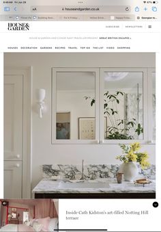 a bathroom with marble counter tops and white cabinets, along with flowers in vases on the sink