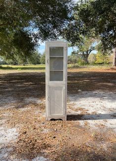 a tall white cabinet sitting in the middle of a field