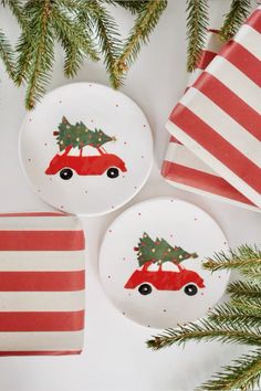 three plates decorated with christmas trees on them next to red and white striped napkins