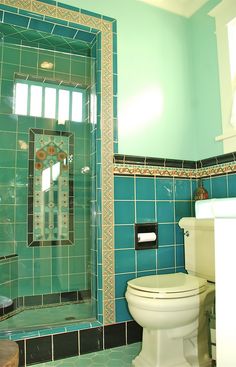 a green tiled bathroom with a toilet and shower