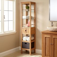 a wooden shelf with towels and baskets on it next to a window in a room