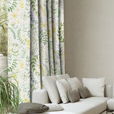 a living room with a white couch and green plants on the wall next to it