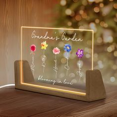 a lighted sign with flowers on it that says grandma's garden