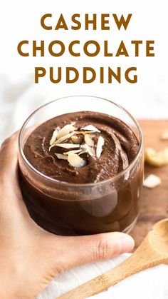 a hand holding a bowl of chocolate pudding with almonds on top and the words cashew chocolate pudding above it