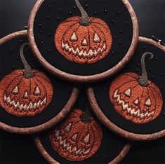 four embroidered pumpkins sitting on top of each other in front of a black background