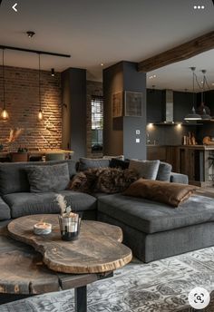 a living room filled with furniture next to a kitchen and dining room table in front of a brick wall