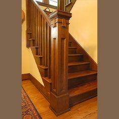 a wooden stair case in a home with hardwood flooring and handrails, along with an area rug